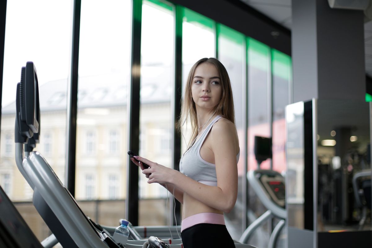Spor salonunda telefonuyla sosyal medya icerigi kontrol eden kadin - sosyal medyadaki fitness efsaneleri
